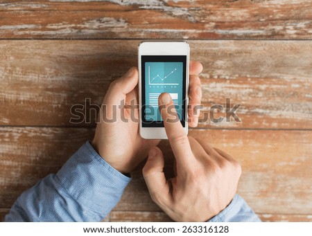 business, education, statistics, people and technology concept - close up of male hands holding smartphone and pointing finger to graph and text on screen at table