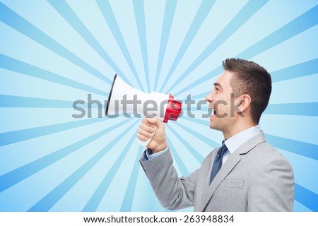 business, people and public announcement concept - happy businessman in suit speaking to megaphone over blue burst rays background