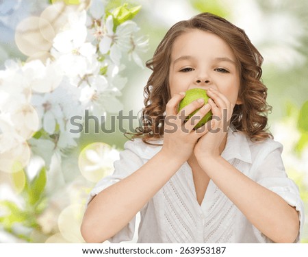 people, children, healthy eating, ecology and food concept- happy girl eating green apple over summer or spring garden background