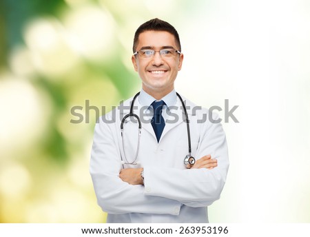 healthcare, profession, people and medicine concept - smiling male doctor in white coat over green background