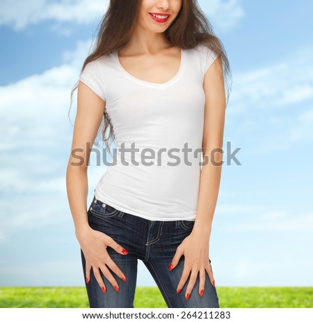 people, advertisement and t-shirt design concept - close up of smiling young woman in blank white t-shirt over blue sky and grass background