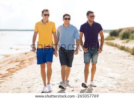 friendship, summer vacation, holidays and people concept - group of smiling male friends in sunglasses walking along beach
