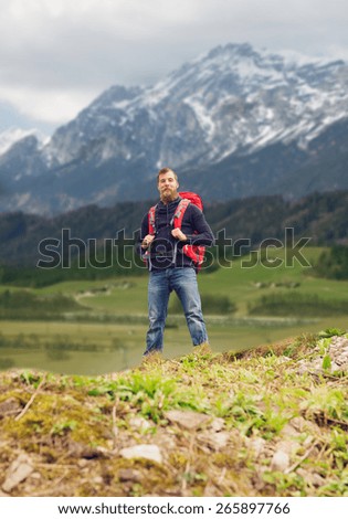 travel, tourism, hike and people concept - tourist with beard and backpack standing on edge of hill over mountains background