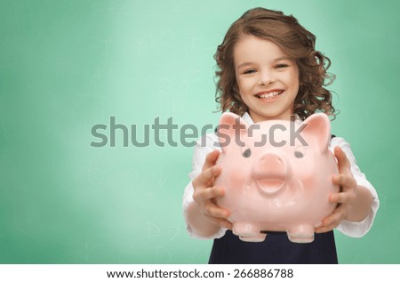 people, money, finances and savings concept - happy girl holding piggy bank over green chalk board background