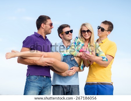 summer, holidays, vacation, happy people concept - group of friends having fun and carrying girl on hands at beach