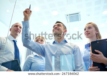 business, people, teamwork and planning concept - smiling business team writing something no notice board with marker in office