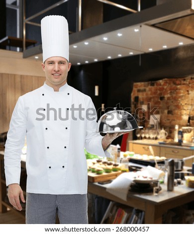 cooking, profession and people concept - happy male chef cook holding cloche over restaurant kitchen