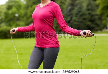 fitness, sport, training, people and lifestyle concept - close up of african american woman exercising with jump-rope outdoors