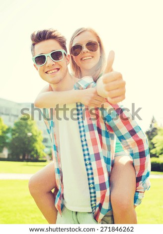 summer holidays, vacation, love, gesture and friendship concept - smiling teen couple in sunglasses having fun and showing thumbs up in park