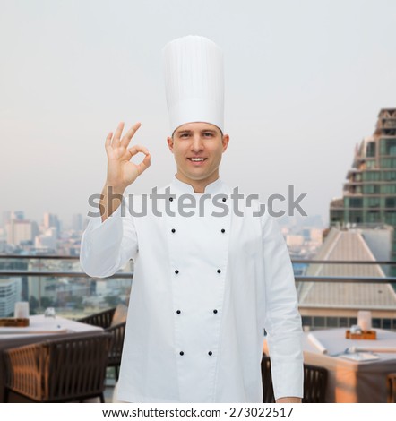 cooking, profession, gesture and people concept - happy male chef cook showing ok sign over city restaurant lounge background