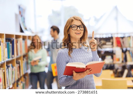 people, knowledge, education and school concept - happy student girl or young woman with book in library