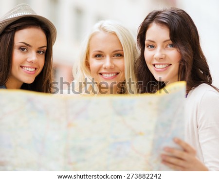 holidays and tourism concept - beautiful girls with map in the city