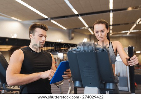 sport, fitness, lifestyle, technology and people concept - woman and trainer with tablet pc computer exercising on stepper in gym