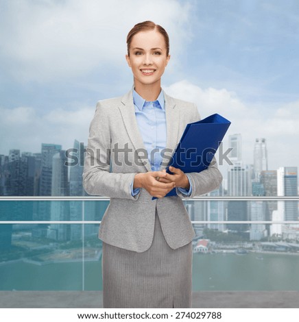 business, people and real estate concept - smiling young businesswoman holding folder over city background