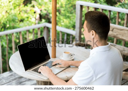 business, people and technology concept - close up of businessman with laptop working outdoors on summer terrace and drinking coffee