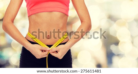 diet, sport, fitness and heath concept - close up of female hands measuring waist with measuring tape
