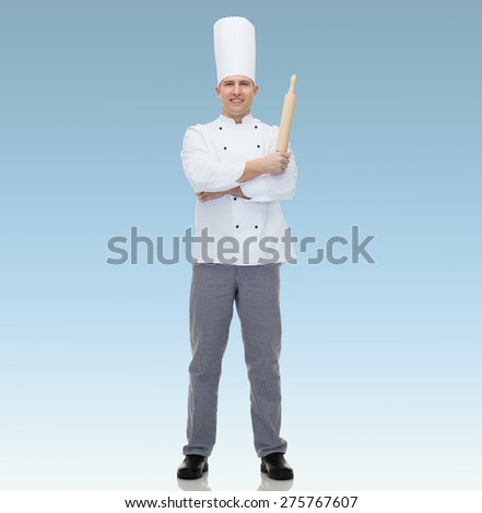 cooking, profession and people concept - happy male chef cook holding rolling pin  over blue background