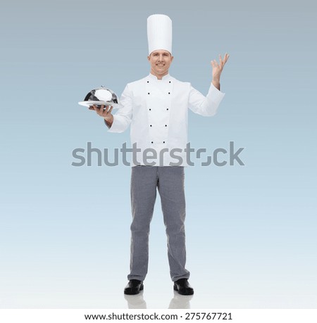 cooking, profession and people concept - happy male chef cook holding cloche  over blue background