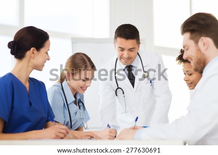 hospital, profession, people and medicine concept - group of happy doctors meeting and taking notes at medical office
