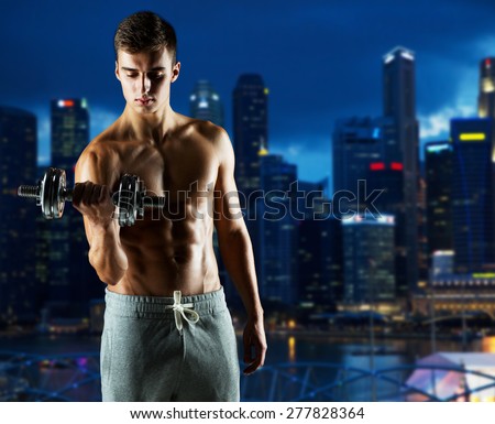 sport, fitness, weightlifting, bodybuilding and people concept - young man with dumbbell flexing biceps over night city background