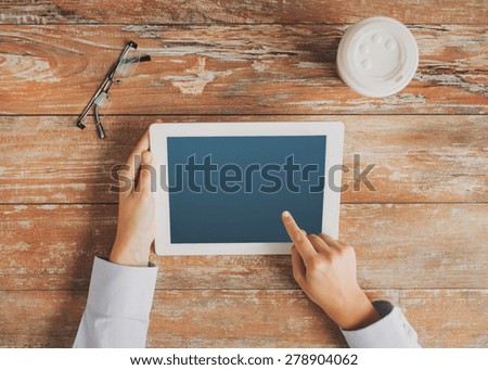 business, education, people, advertisement and technology concept - close up of hands pointing finger to tablet pc computer screen with coffee cup and eyeglasses on table
