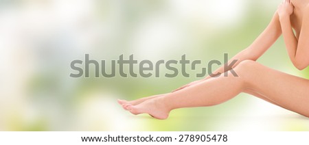 people, beauty, health and body care concept - close up of naked woman legs over green background