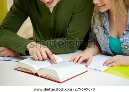 education, people and school concept - close up of happy students reading textbook or book at school
