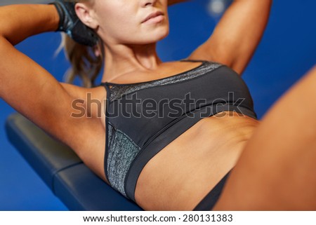 fitness, sport, training and lifestyle concept - close up of woman flexing abdominal muscles on bench in gym