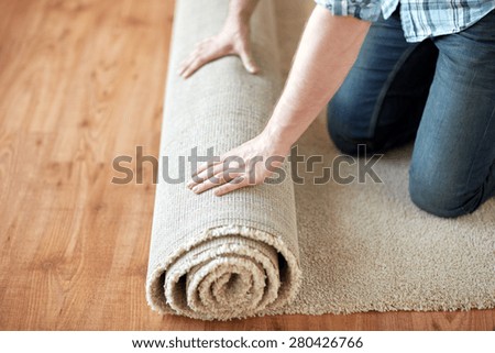 repair, building and home concept - close up of male hands rolling carpet