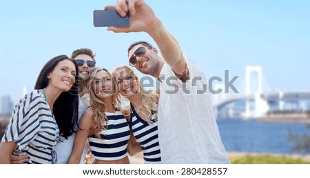 summer, tourism, asia, technology and people concept - group of smiling friends taking selfie with smartphone over rainbow bridge in japan background