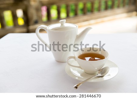 drinks, relaxation and tea party concept - tea-set of cup, pot, spoon and saucer at teahouse