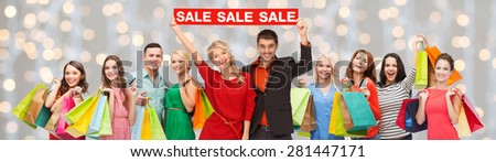 consumerism, people and discount concept - group of happy people with sale sign and shopping bags over holidays lights background