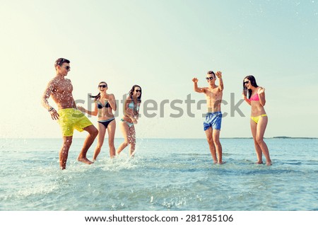 friendship, sea, summer vacation, holidays and people concept - group of happy friends having fun on summer beach