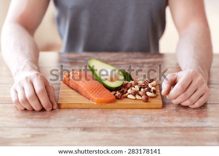healthy lifestyle, diet and people concept - close up of male hands with food rich in protein on cutting board on table