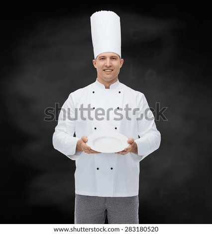 cooking, profession, advertisement and people concept - happy male chef cook showing something on empty plate over black chalk board background
