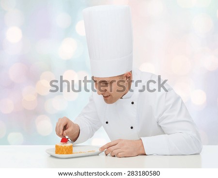 cooking, profession, haute cuisine, food and people concept - happy male chef cook decorating dessert over blue lights background