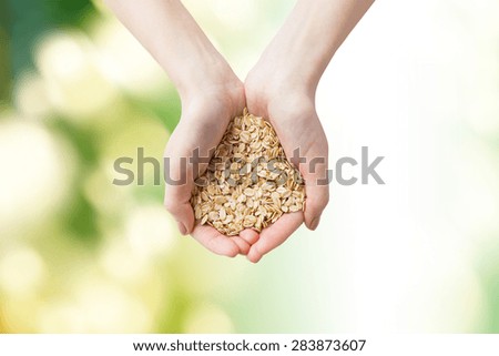healthy eating, dieting, vegetarian food and people concept - close up of woman hands holding oatmeal flakes over green natural background