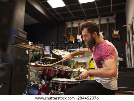 music, sale, people, musical instruments and entertainment concept - male musician playing cymbals at music store