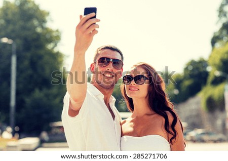 love, wedding, summer, dating and people concept - smiling couple wearing sunglasses making selfie with smartphone in park