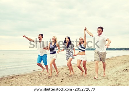 summer, holidays, sea, tourism and people concept - group of smiling friends in sunglasses running on beach