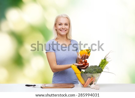 healthy eating, cooking, vegetarian food, dieting and people concept - smiling young woman with bowl of vegetables over green natural background