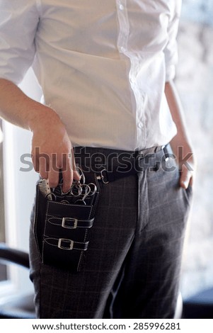 beauty, hairstyle and people concept - close up of male stylist with tool case on belt at salon