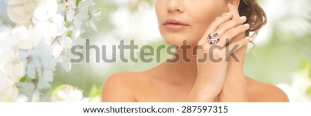 beauty, jewelry, people and accessories concept - close up of woman with cocktail ring on hand over summer garden and cherry blossom background