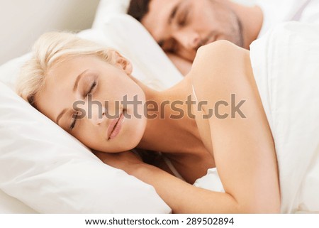 people, family, bedtime and happiness concept - happy couple sleeping in bed at home