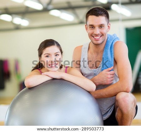fitness, sport, training, gym and lifestyle concept - two smiling people with fitness ball in the gym