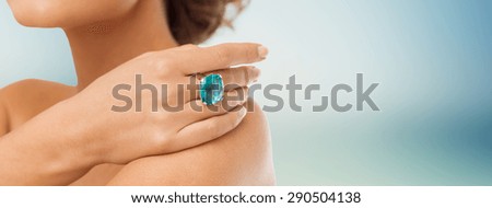 beauty, jewelry, people and accessories concept - close up of woman with cocktail ring on hand over blue background