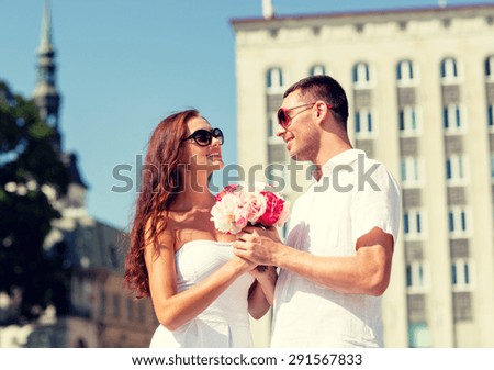love, wedding, summer, dating and people concept - smiling couple wearing sunglasses with bunch of flowers looking at each other in city