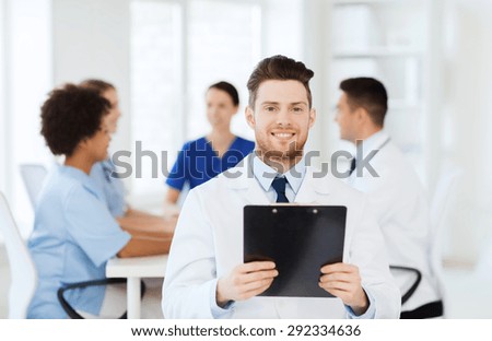 clinic, profession, people and medicine concept - happy male doctor with tablet pc computer over group of medics meeting at hospital