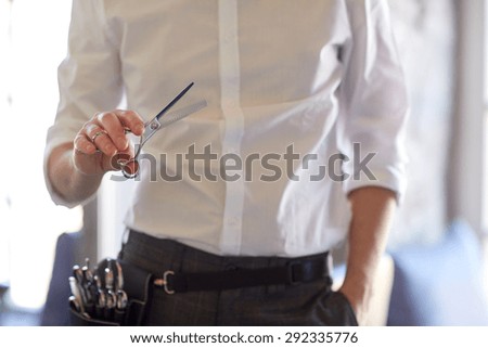 beauty, hairstyle and people concept -close up of male stylist with scissors at salon