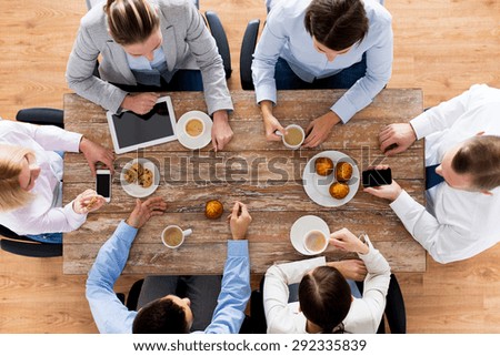 business, people, break and team work concept - close up of creative team meeting and drinking coffee with muffins during lunch in office